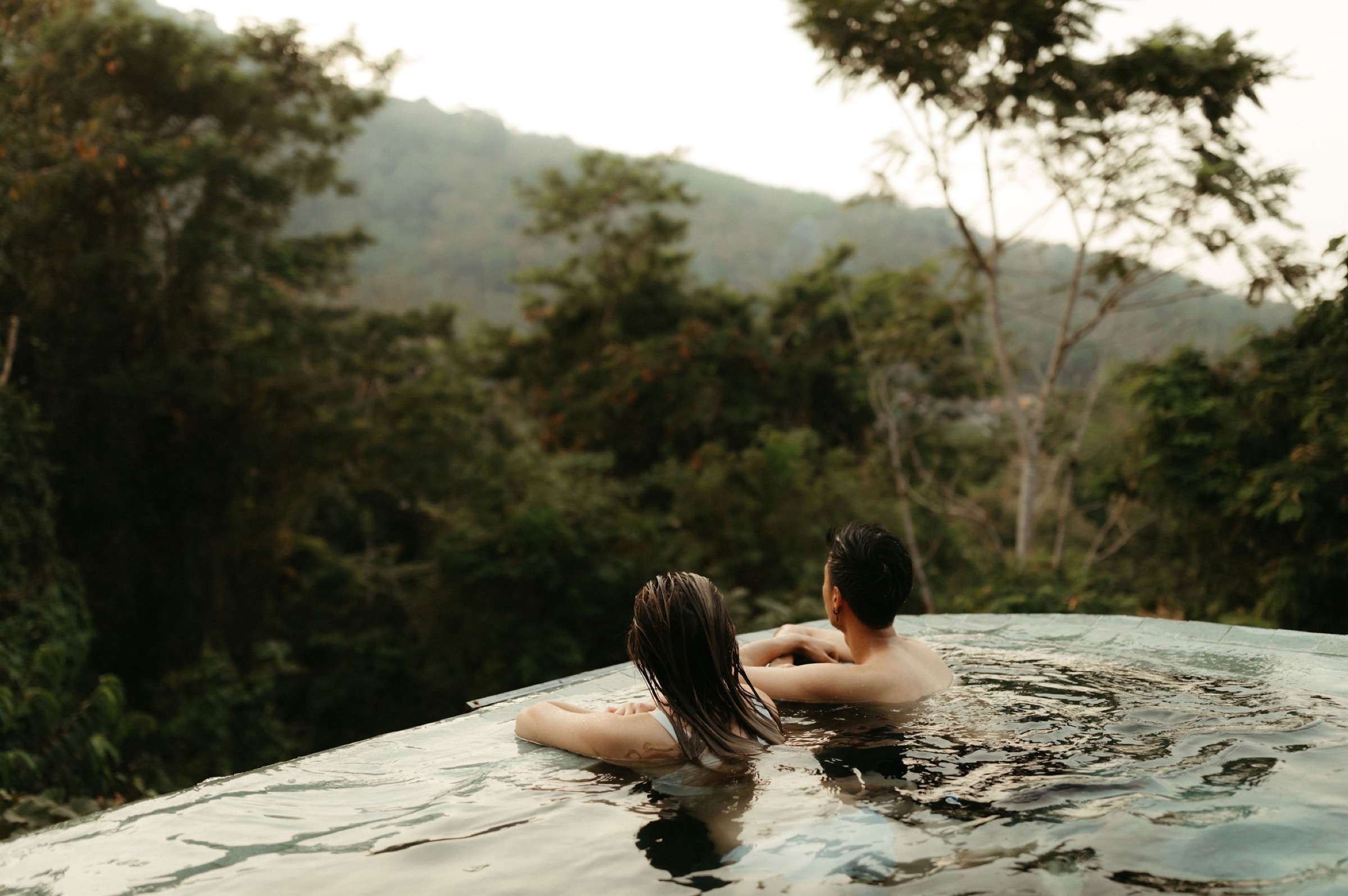 adventurous travel couple in white bikini enjoying their honeymoon in thailand in infinity pool