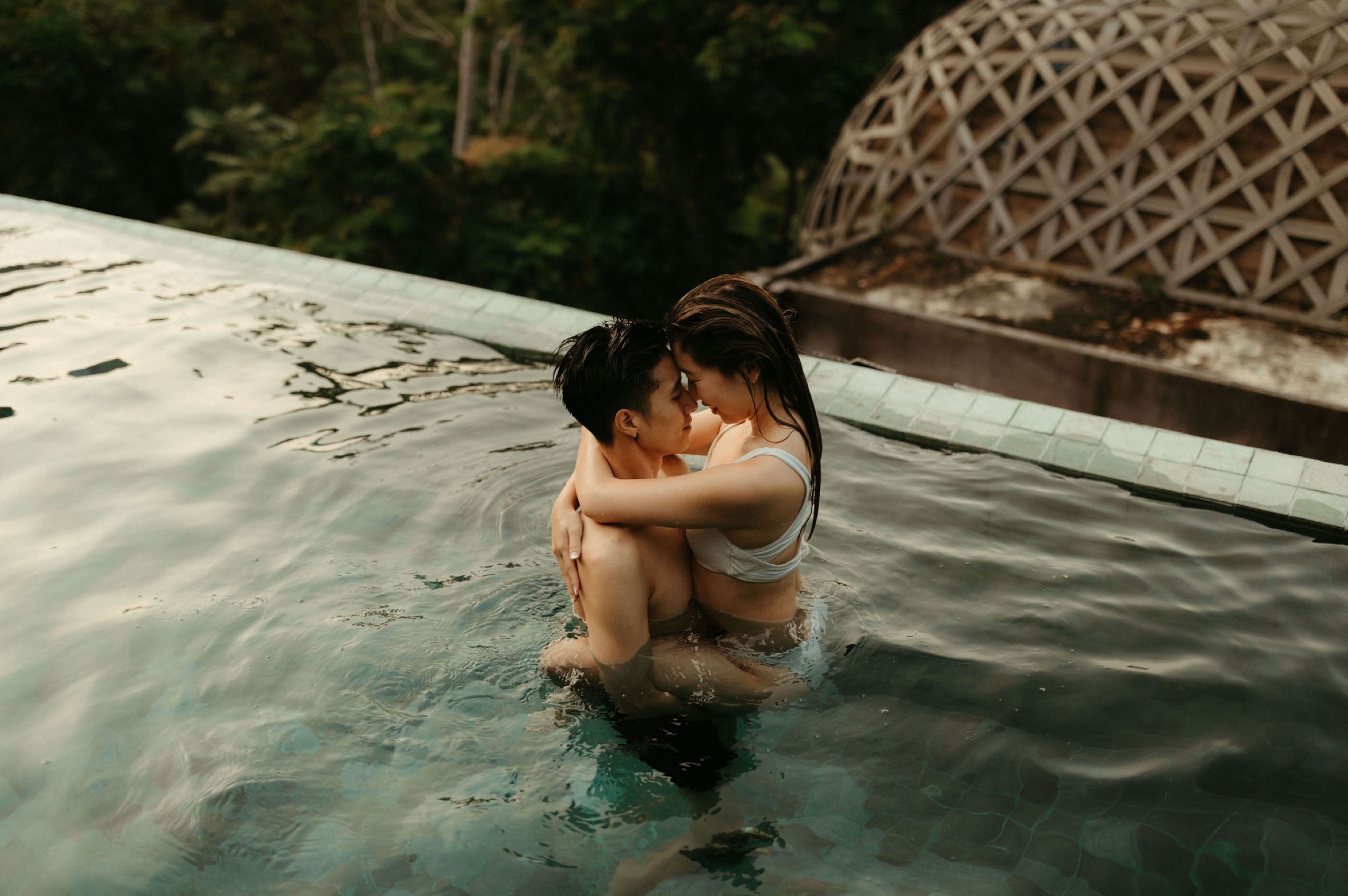 adventurous travel couple in white bikini enjoying their honeymoon in thailand in infinity pool