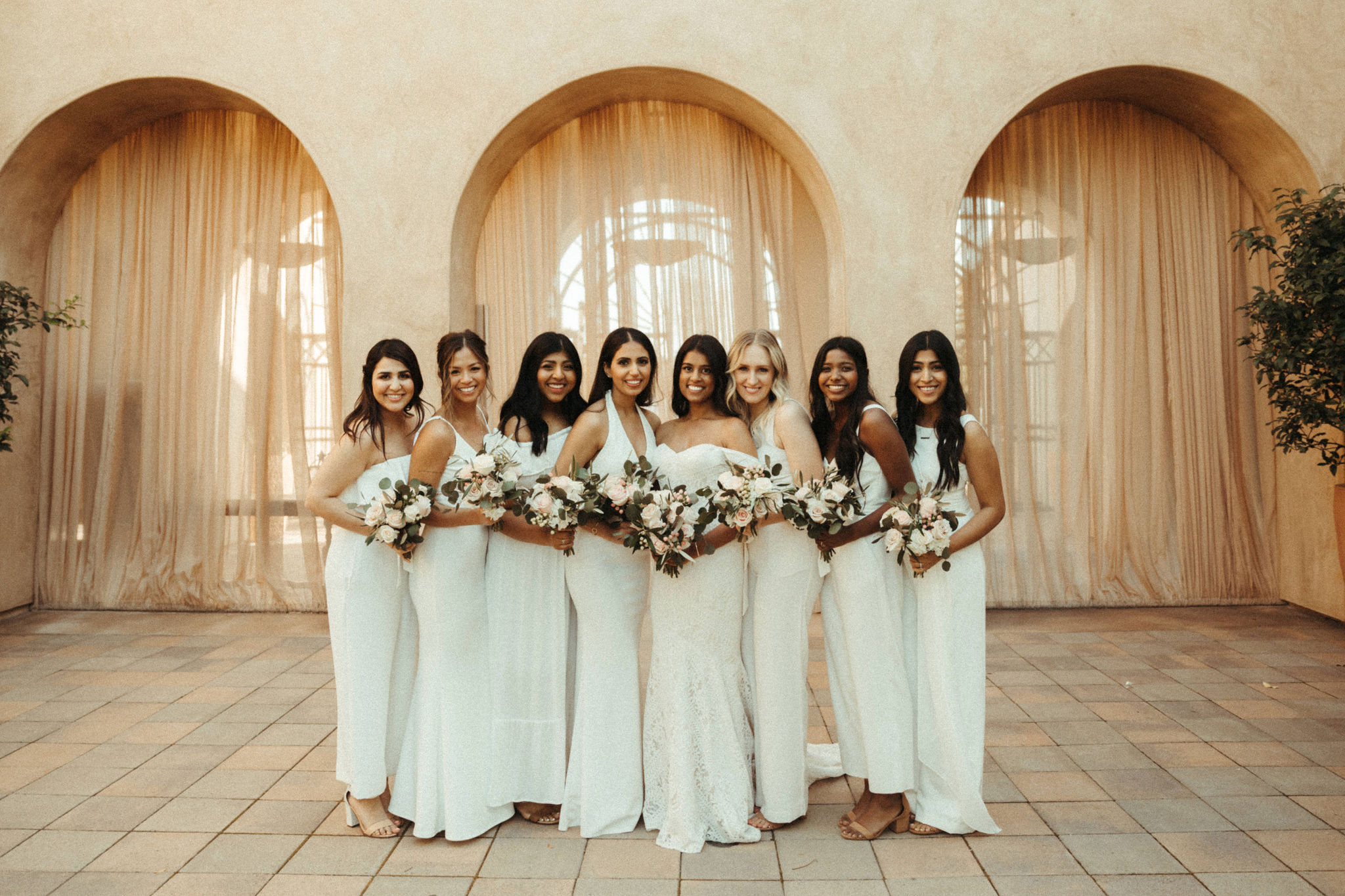 Beautiful bridesmaids in all white dresses and jumpsuits at a san juan capistrano wedding venue