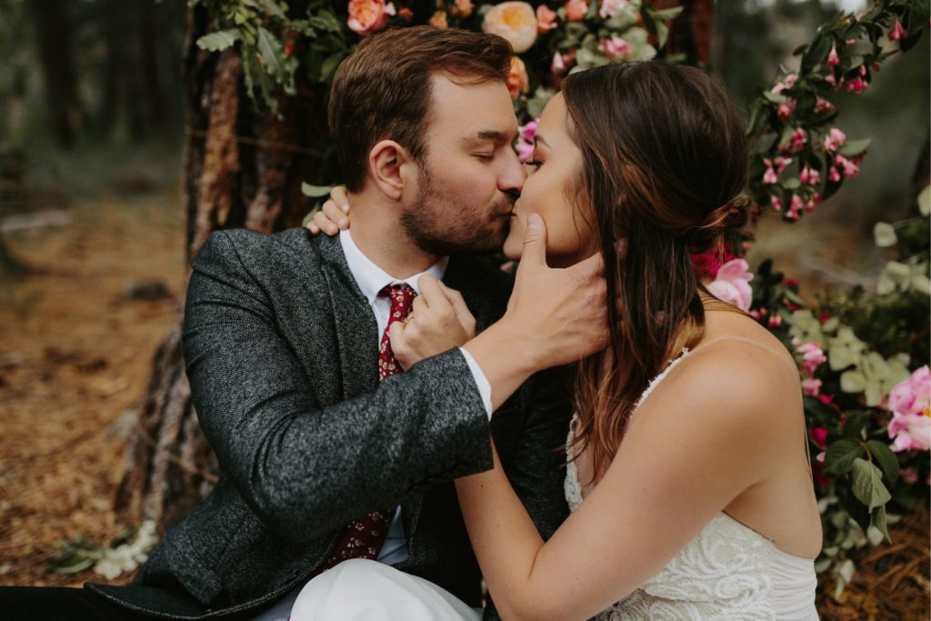 bride and groom in the forest with incredible floral ceremony backdrop