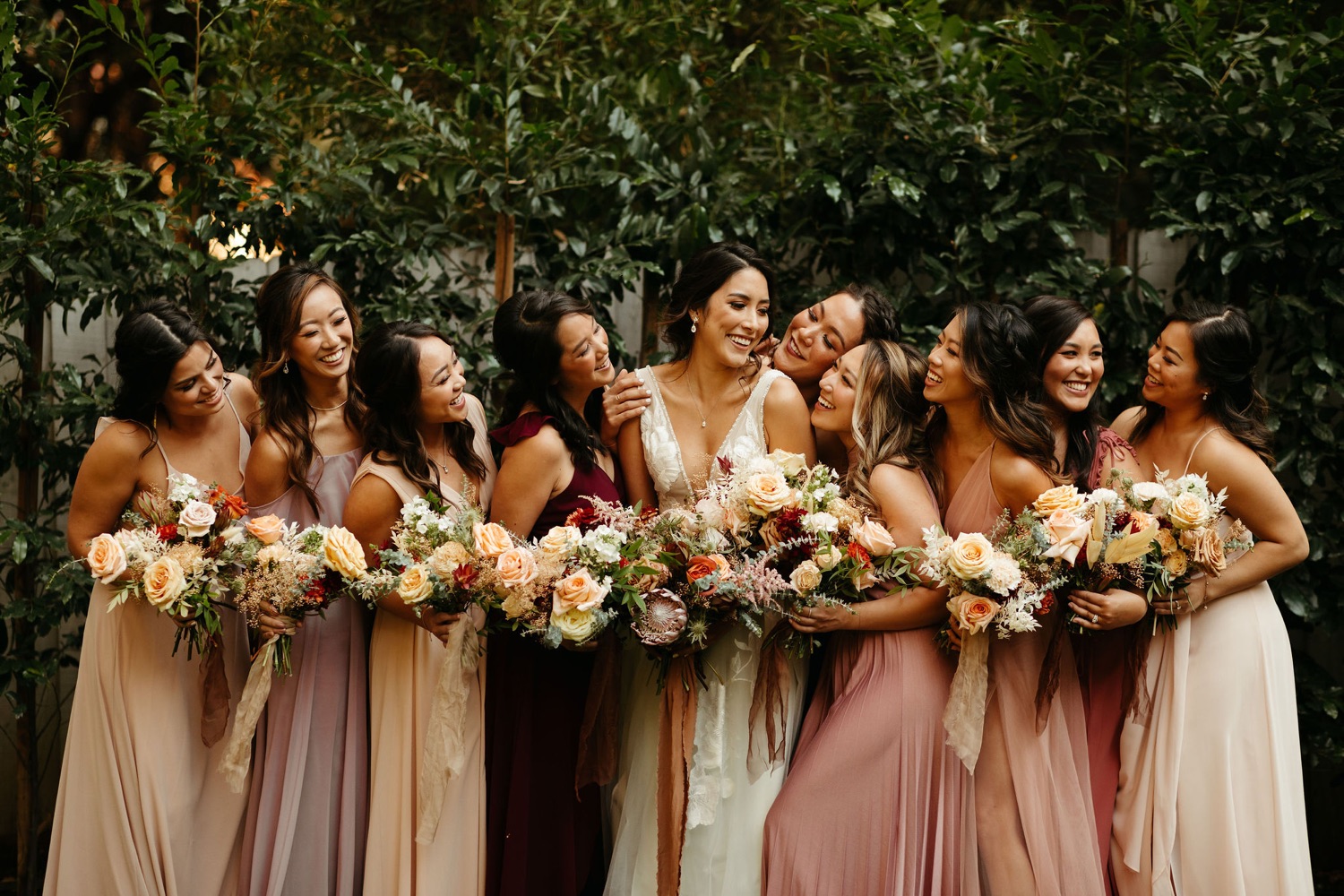 beautiful laughing bridesmaids in blush, lavender, and ivory dresses and bouquets