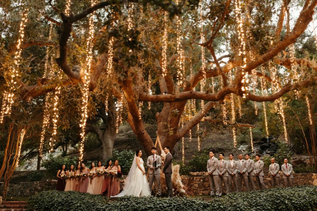 magical calamigos ranch wedding with beautiful hanging lights in the trees, and triangle ceremony arch