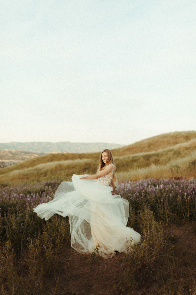 natural candid bride running around in her wedding dress in some lupine fields