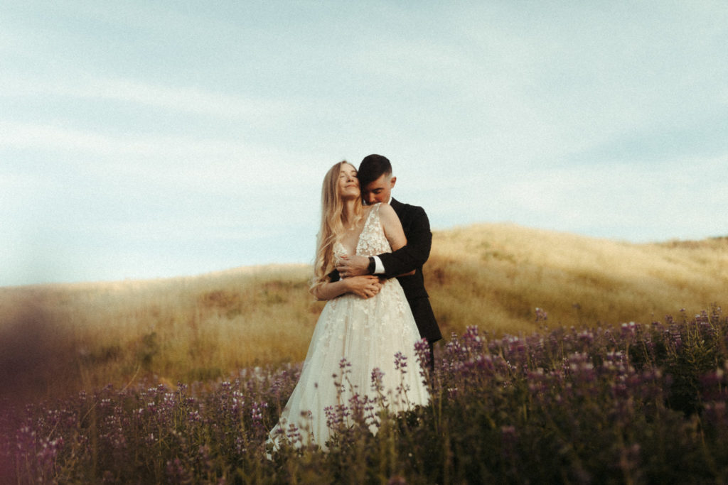 beautiful bride and groom in the iceland lupine fields for their sunrise elopement