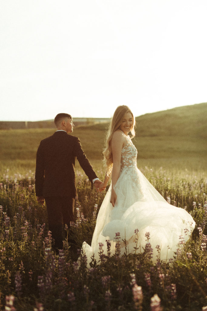bride and groom running in the fields at sunrise on their wedding elopement day