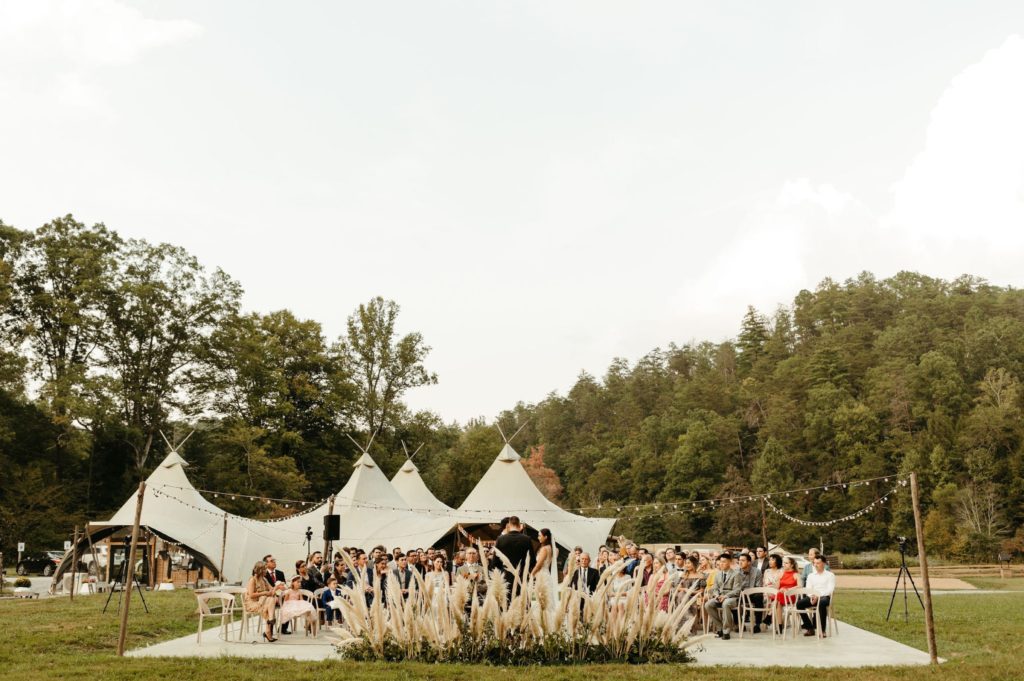 under canvas smoky mountains festival wedding ceremony with pampas grass and tents