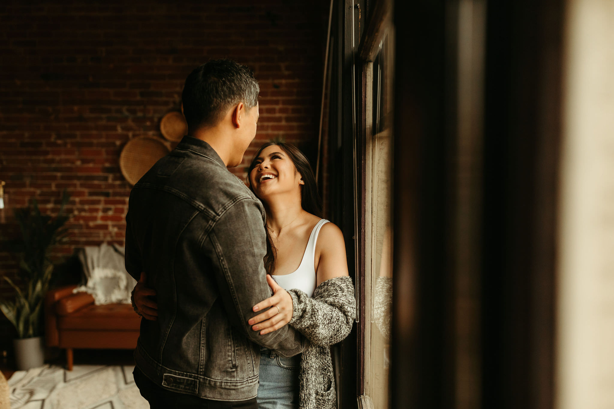 couple in their Seattle loft with exposed brick walls and floor to ceiling windows