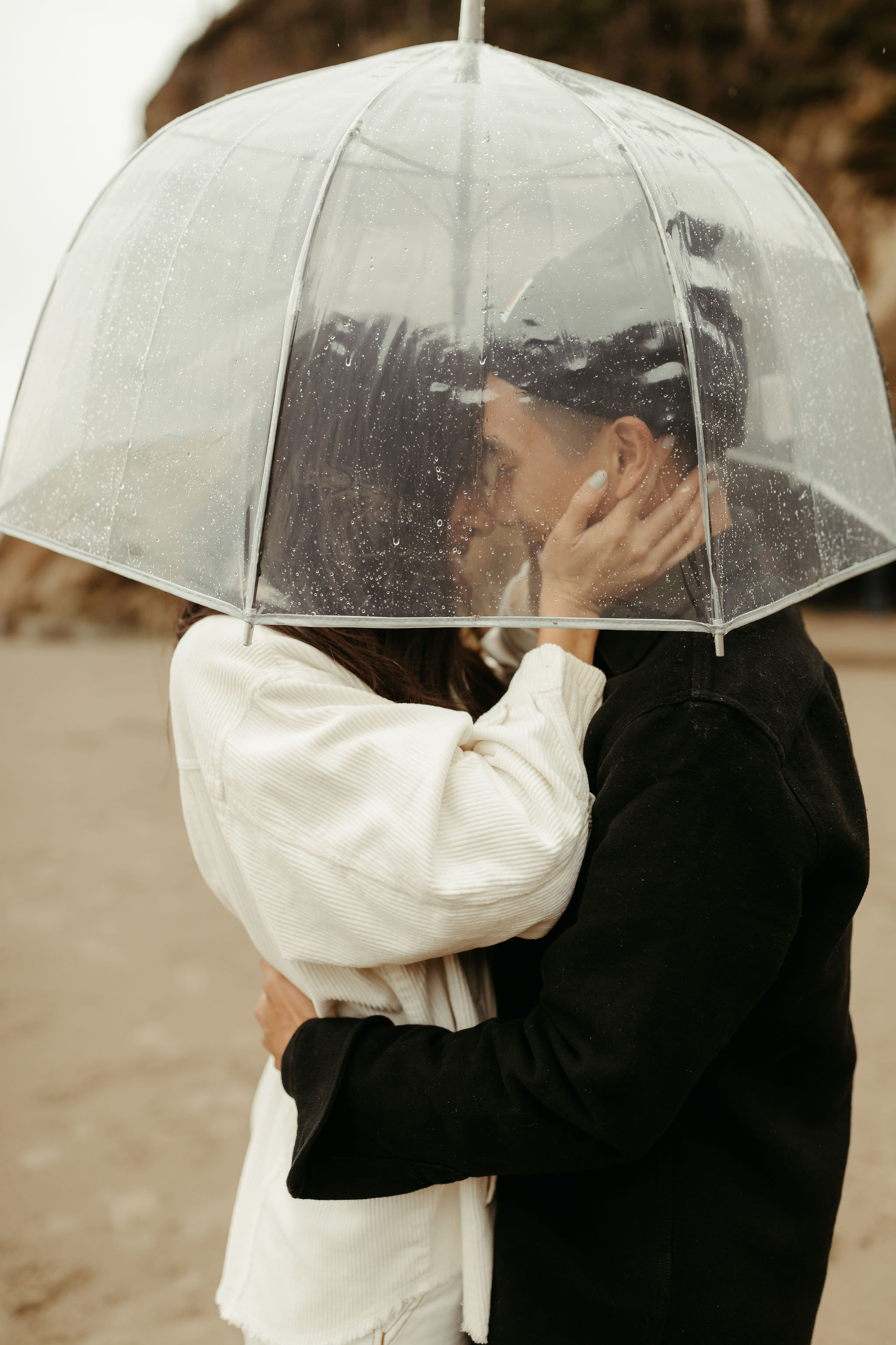 couple embracing under clear umbrella on a rainy day