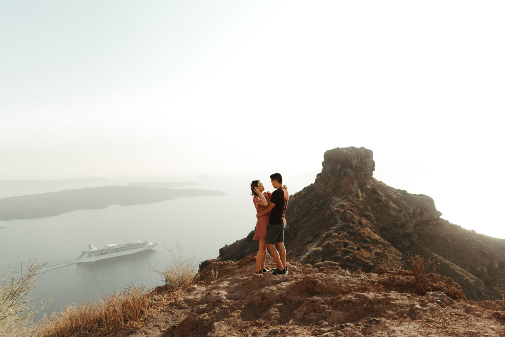 santorini engagement session at volcano with boat in background