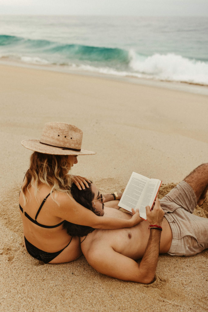 couple reading book together on the beach in cabo
